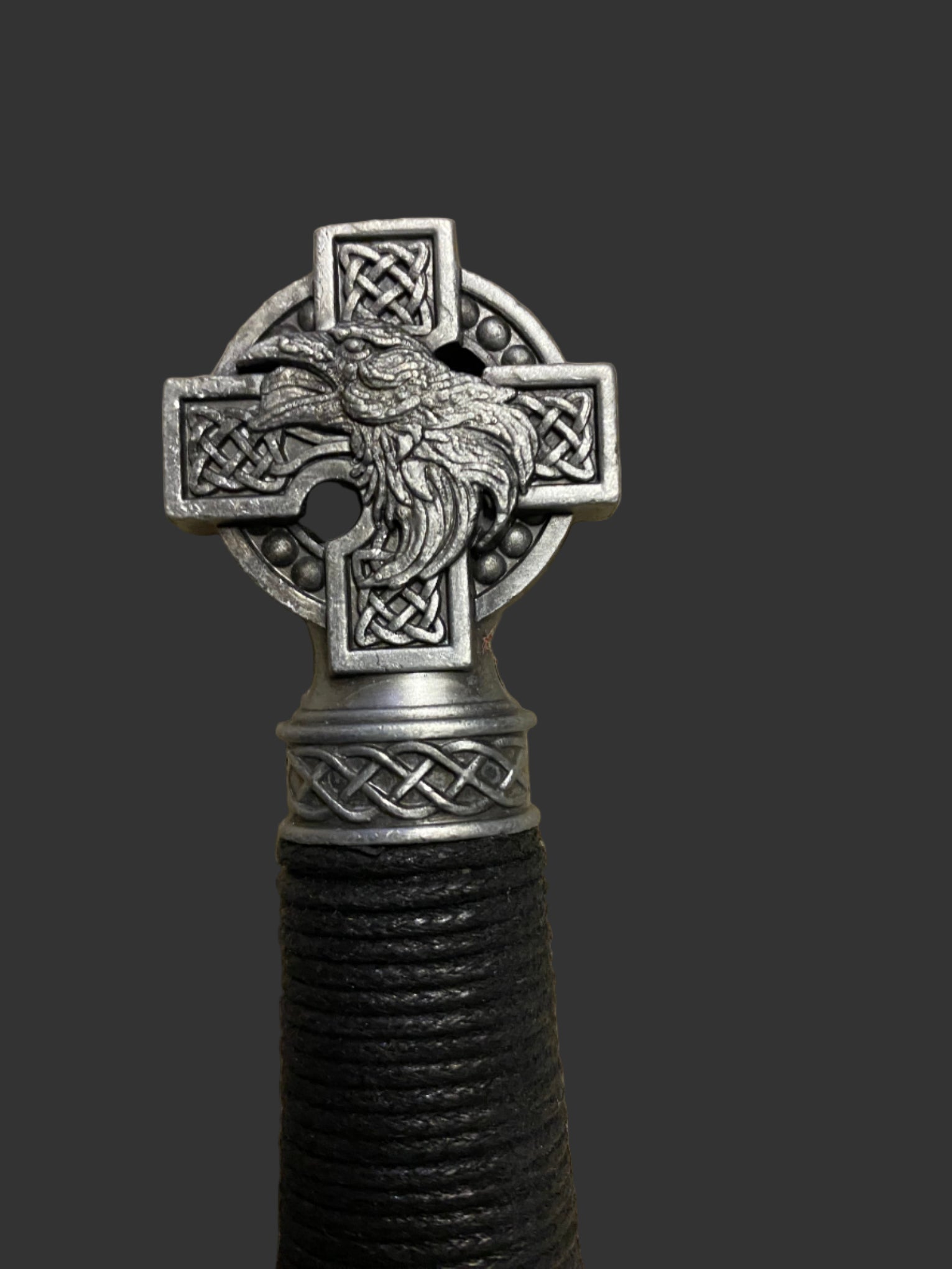 Decorative object with Celtic cross design featuring a bird, on a dark background.