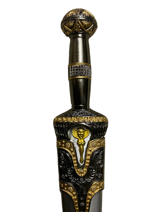 Decorative sword handle with intricate gold and black design on a white background