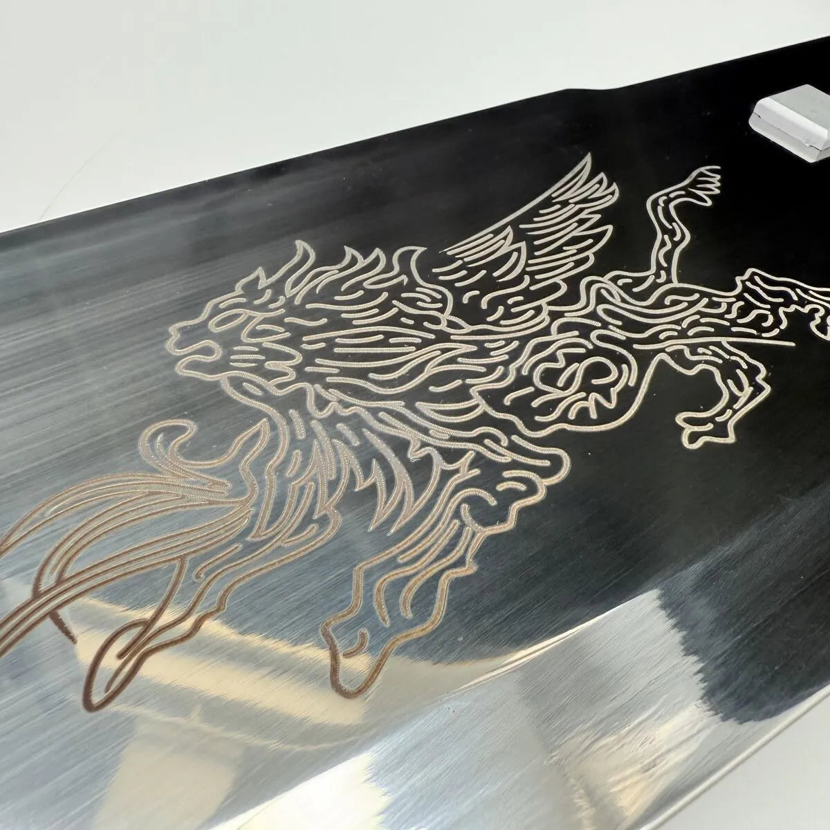 Metallic surface with a detailed dragon engraving on a reflective background
