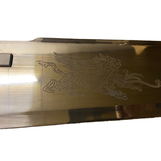 Gold-colored object with a engraved design on a white background