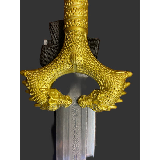 Decorative gold hilt of a sword on a dark background