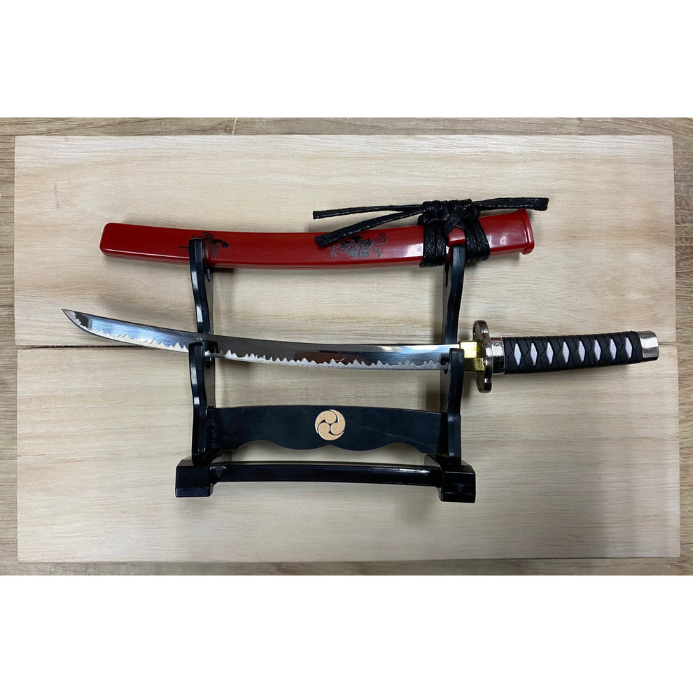 Sword with red sheath on a wooden stand against a light wood panel background