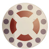 Decorative plate with purple polka dots and red geometric shapes on a beige background