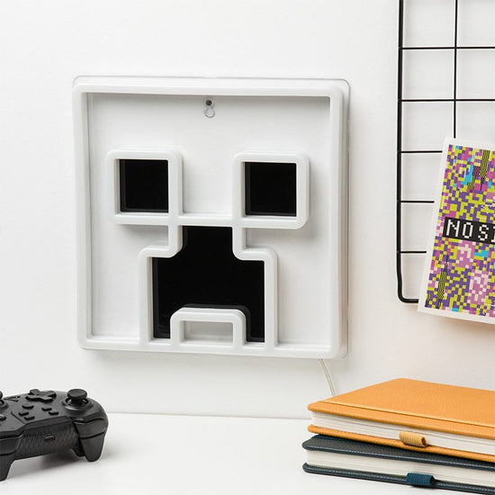 White wall art with black geometric design on a white surface with books and a controller.