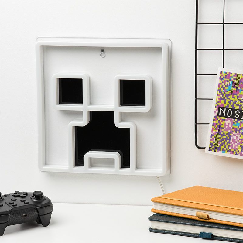 White wall art with black geometric design on a white surface with books and a controller.