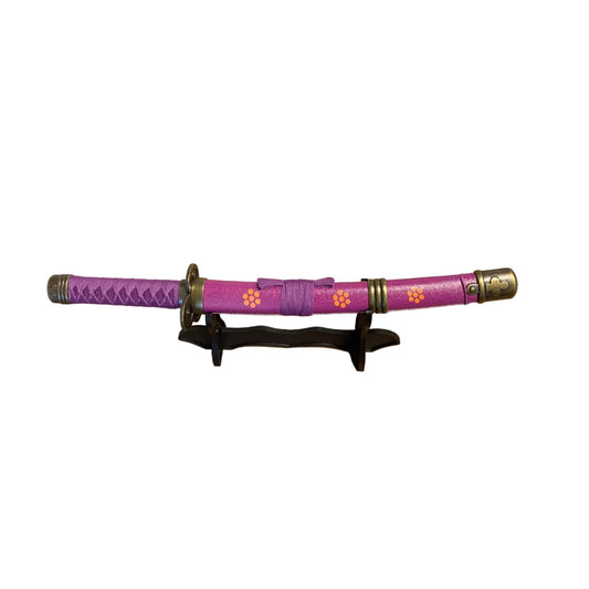 Purple  sword with decorative elements on a stand against a plain background