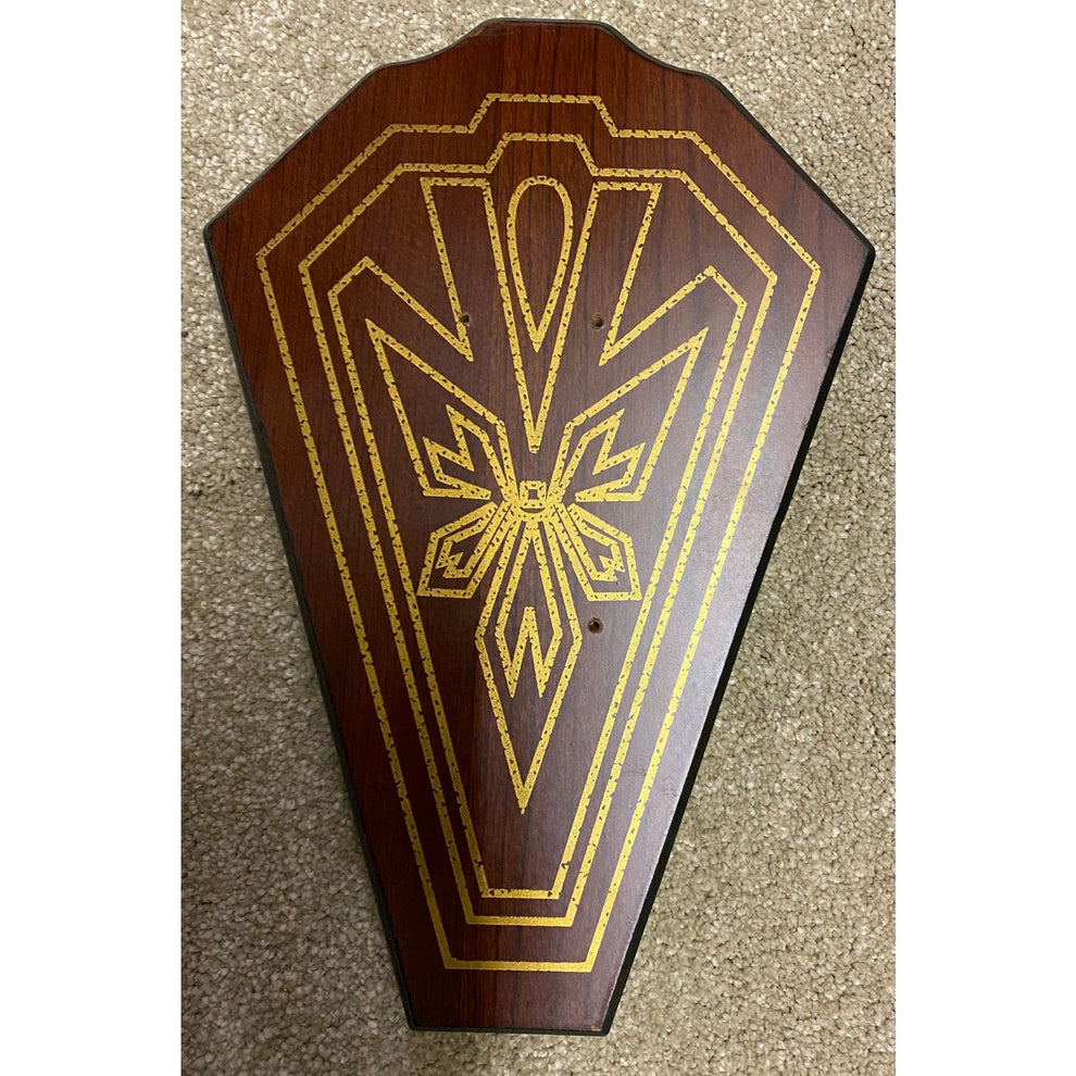 Decorative wooden panel with gold intricate design on a textured surface