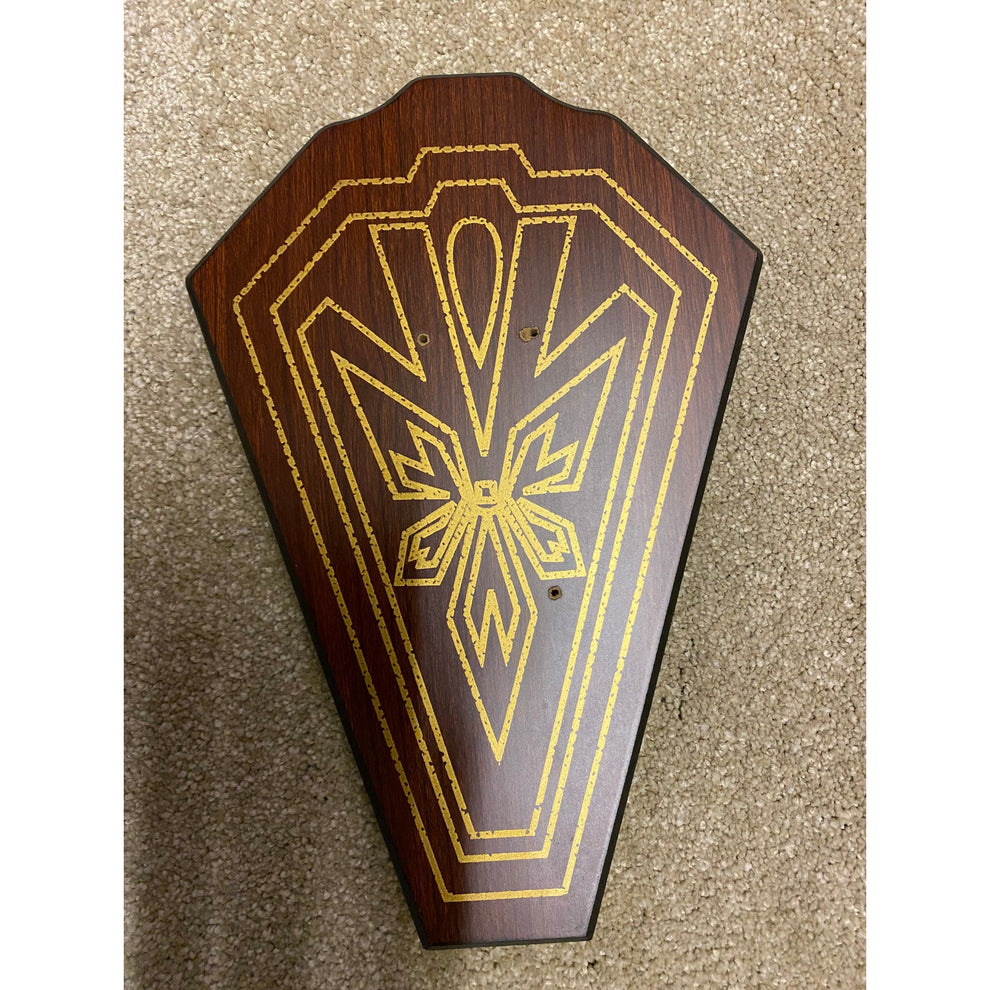Wooden plaque with gold geometric design on a textured surface