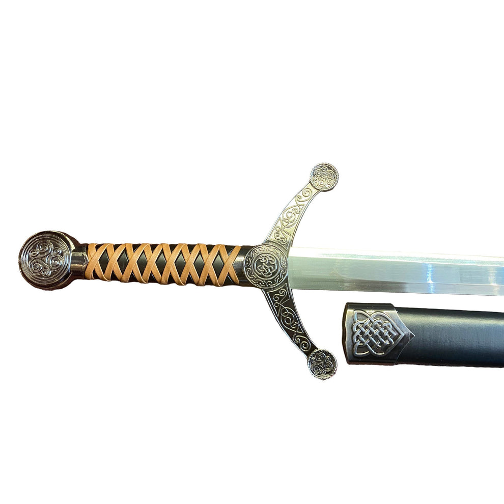Decorative sword with ornate handle on a textured brown surface