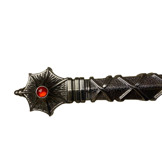 Decorative object with star design and red gemstone on a textured surface