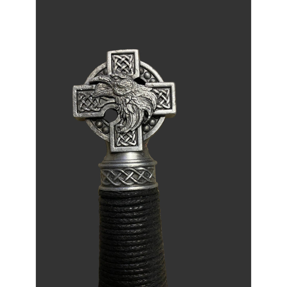 Decorative object with Celtic cross design featuring a bird, on a dark background.