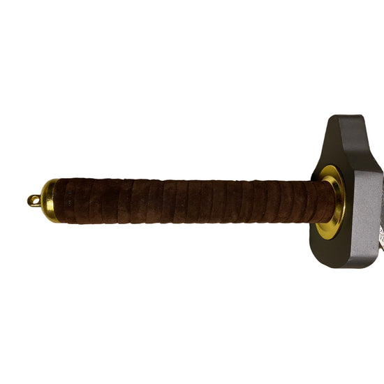 Sword handle with brown grip and gold accents on a beige carpet